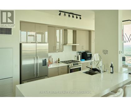 A modern kitchen with a refrigerator, stove, and sink.