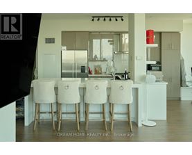 A modern kitchen with white chairs and a wooden table.