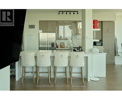 A modern kitchen with white chairs and a wooden table.