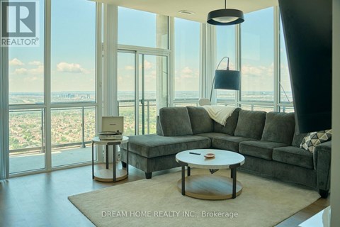 A modern living room with a grey sofa and a coffee table in front of a large window.
