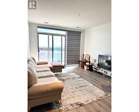 A living room with a couch, a rug, a television, and a window with blinds.