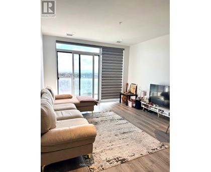 A living room with a couch, a rug, a television, and a window with blinds.