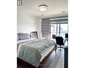 A bedroom with a bed, a chair, and a window with blinds.