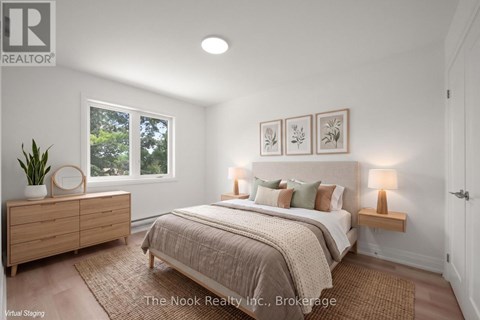 A bedroom with a bed, nightstands, and a plant.