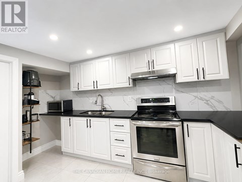 A kitchen with white cabinets and black countertops.
