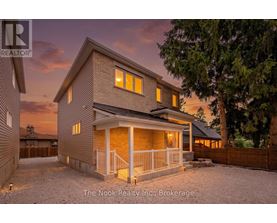 A house with a porch and a fence in front of it.