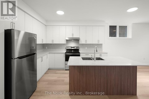 A modern kitchen with a stainless steel refrigerator and wooden island.