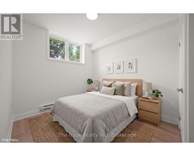 A bedroom with a bed, nightstand, and a window.
