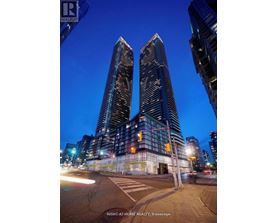 Two tall buildings are shown at night with a street in front of them.