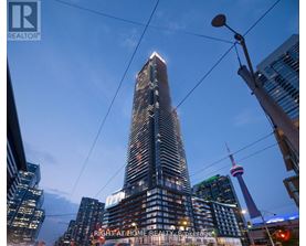 A tall building with a glass facade stands in the foreground of a cityscape.