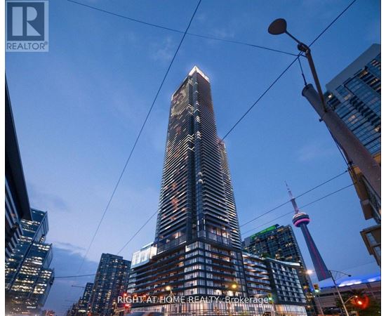 A tall building with a glass facade stands in the foreground of a cityscape.