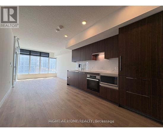 A modern kitchen with dark wood cabinets and stainless steel appliances.