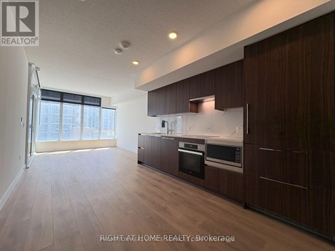 A modern kitchen with dark wood cabinets and stainless steel appliances.
