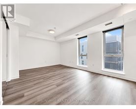 A spacious room with wooden flooring and white walls.