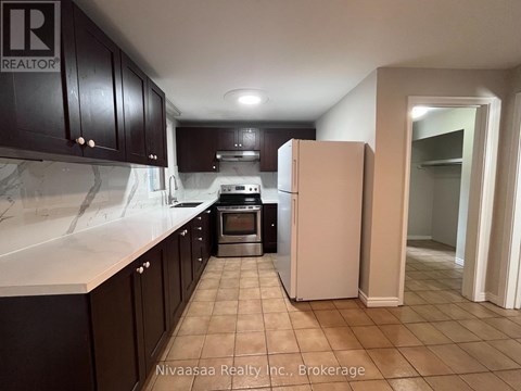 A kitchen with a refrigerator, oven, and cabinets.