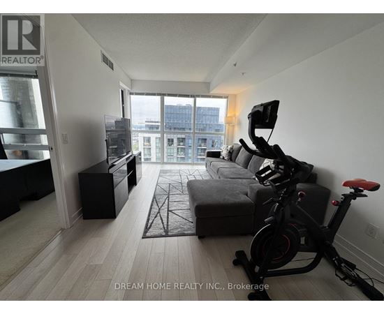 A living room with a grey sofa and a black exercise bike.