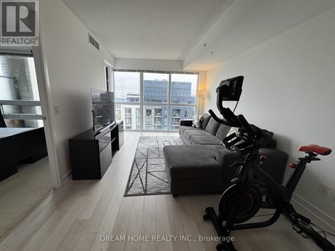 A living room with a grey sofa and a black exercise bike.