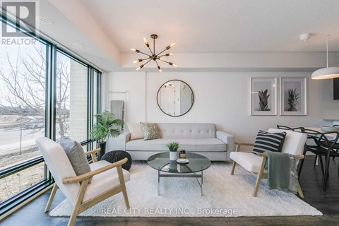 A well-lit living room with a white couch, a glass coffee table, and a large window.