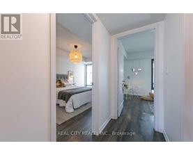 A bedroom with a bed and a lamp hanging from the ceiling.
