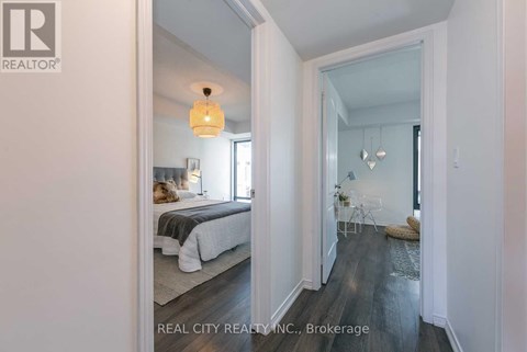 A bedroom with a bed and a lamp hanging from the ceiling.