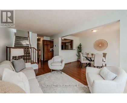 A living room with a staircase and a dining area.