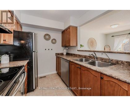 A kitchen with a black refrigerator, wooden cabinets, and a granite countertop.
