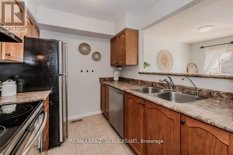 A kitchen with a black refrigerator, wooden cabinets, and a granite countertop.