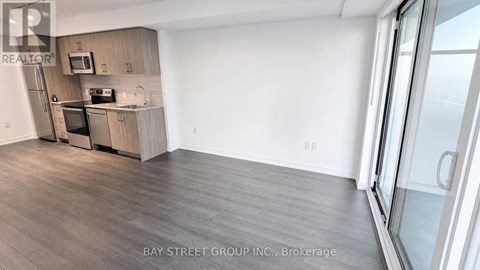 A kitchen with a refrigerator, microwave, and oven.