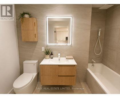 A bathroom with a toilet, sink, mirror, and bathtub.