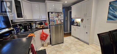 A kitchen with white cabinets and a black counter top.