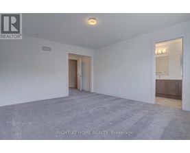 A spacious room with a carpeted floor and white walls, with a doorway leading to another room.