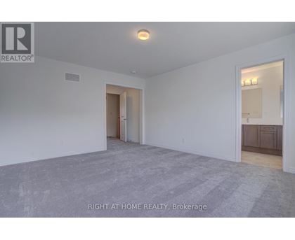 A spacious room with a carpeted floor and white walls, with a doorway leading to another room.