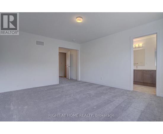 A spacious room with a carpeted floor and white walls, with a doorway leading to another room.