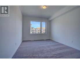 A room with a carpeted floor and a window showing a view of apartment buildings.