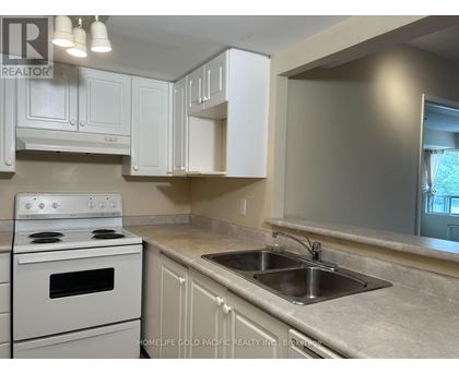 A kitchen with a white stove and cabinets.