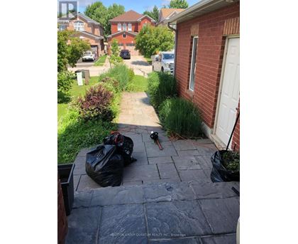 A red brick house with a white door and a black trash bag on the ground.