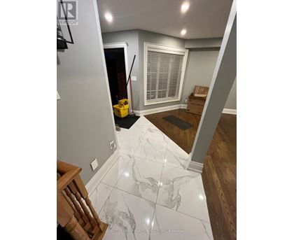 A hallway with a marble floor and a wooden staircase.