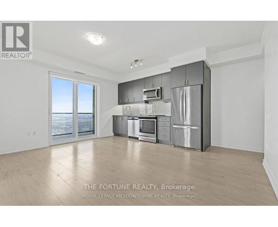 A spacious kitchen with stainless steel appliances and a large window overlooking the city.