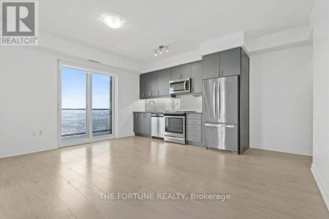 A spacious kitchen with stainless steel appliances and a large window overlooking the city.