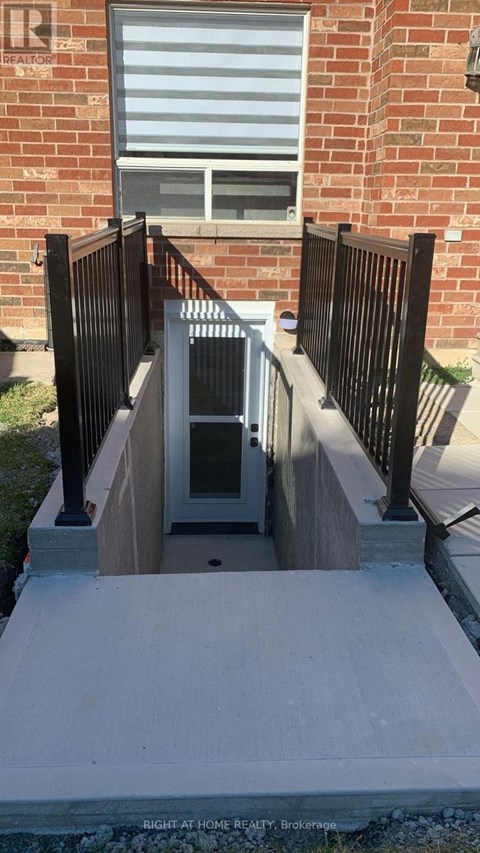 A small doorway with a black railing and a brick wall behind it.