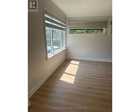 A room with wooden flooring and a window with blinds.