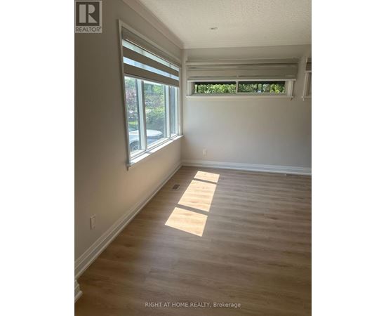 A room with wooden flooring and a window with blinds.