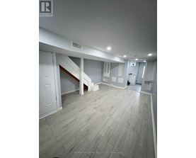 A spacious room with wooden flooring and white walls.