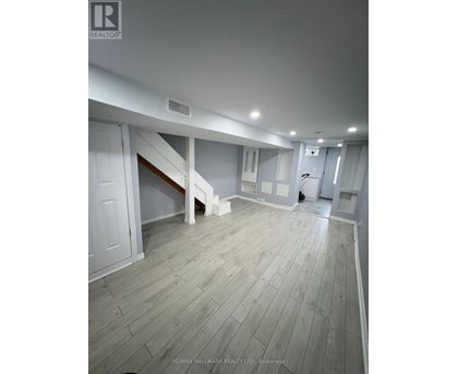 A spacious room with wooden flooring and white walls.