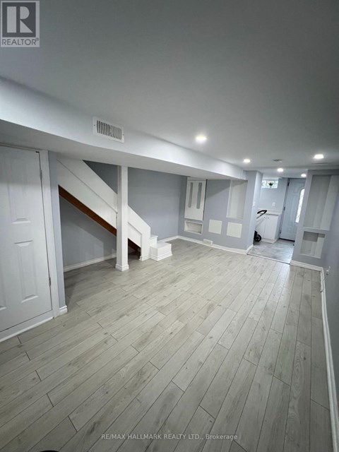 A spacious room with wooden flooring and white walls.