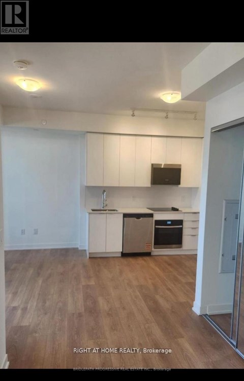 A kitchen with white cabinets and a wooden floor.