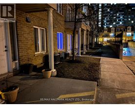 A nighttime view of a residential street with a RE/MAX Hallmark Realty Ltd. sign in the foreground.