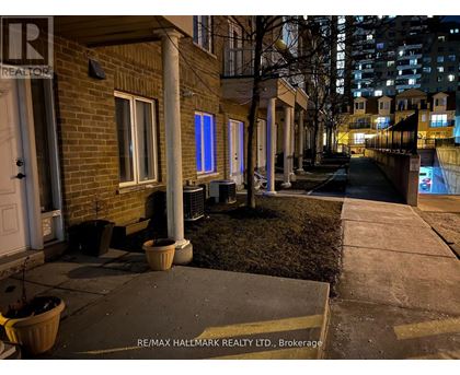 A nighttime view of a residential street with a RE/MAX Hallmark Realty Ltd. sign in the foreground.