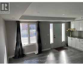 A well-lit, spacious room with a large window and a door leading to another room.