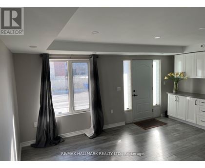 A well-lit, spacious room with a large window and a door leading to another room.